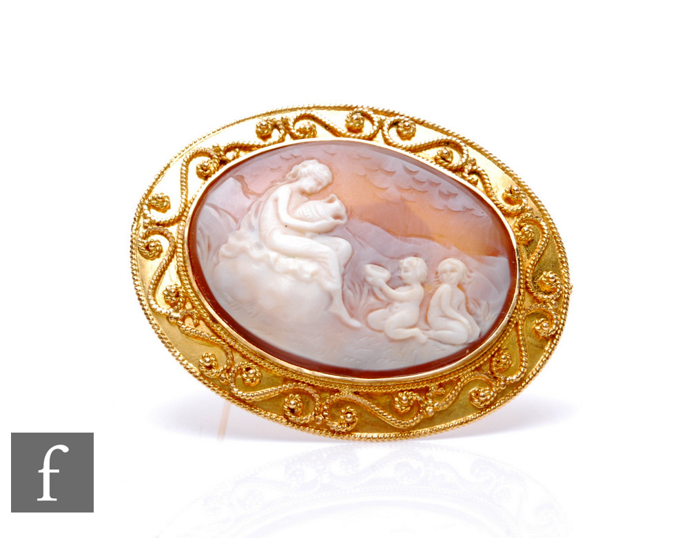 An 18ct mounted oval cameo brooch, landscape scene of a woman and children in attendance, weight