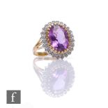 A 9ct hallmarked amethyst and diamond cluster ring, central amethyst within a border of diamonds,