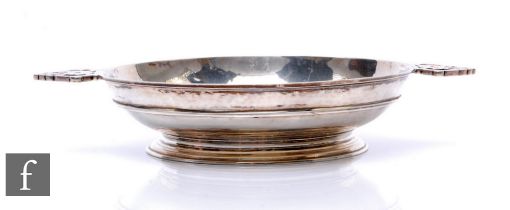 A hallmarked silver twin handle shallow bowl with planished decoration above a collet foot, weight