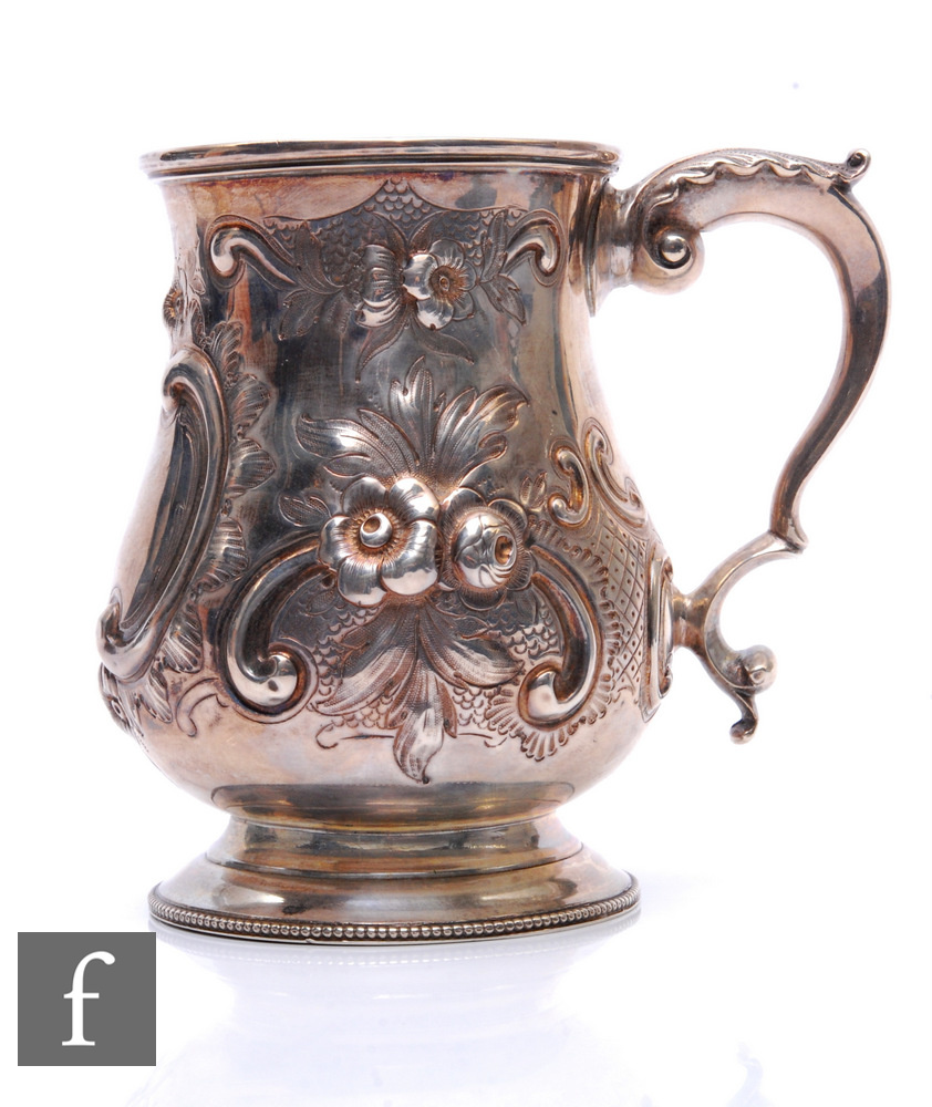 A Victorian hallmarked silver baluster tankard with foliate engraved and embossed decoration to