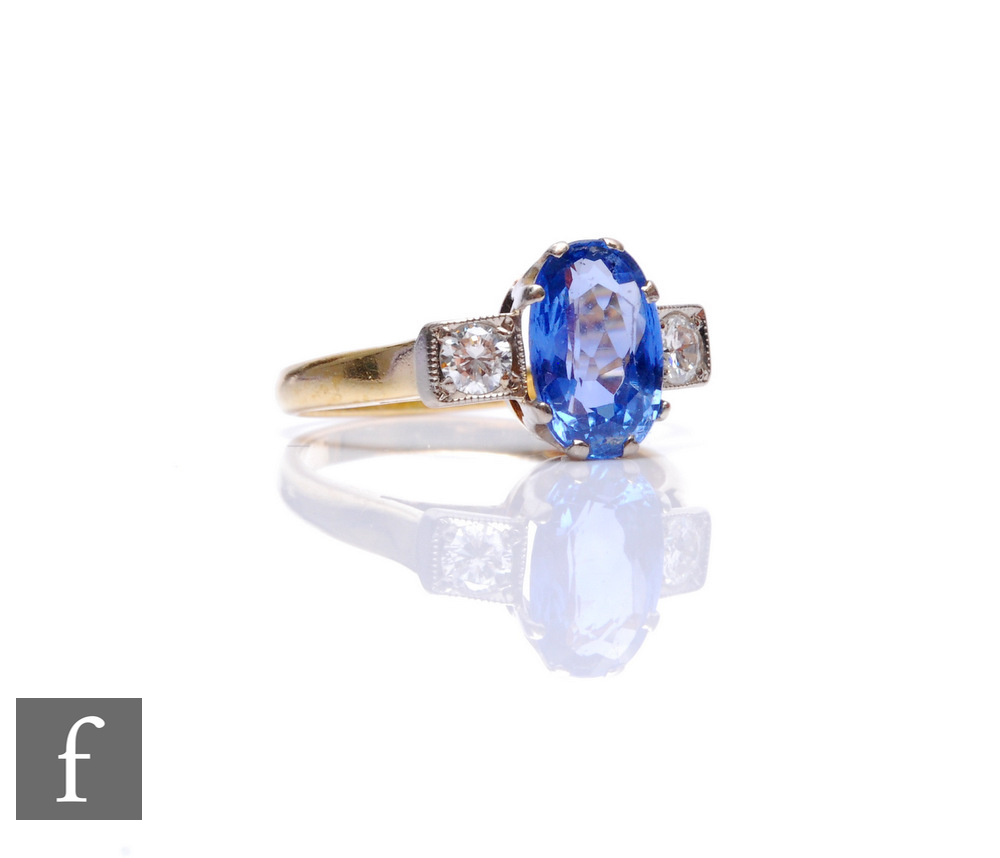 An 18ct hallmarked sapphire and diamond three stone ring, central oval cornflower blue sapphire