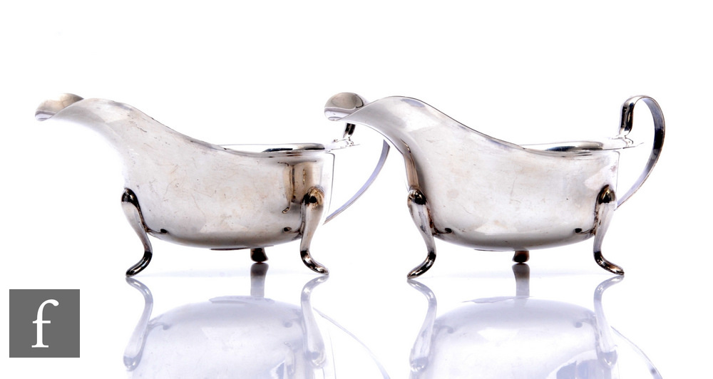 A pair of hallmarked silver sauce boats, each raised on three pad feet and terminating in waved