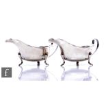 A pair of hallmarked silver sauce boats, each raised on three pad feet and terminating in waved