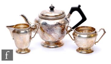 A hallmarked silver three piece pedestal tea set each with a circular stepped base below plain