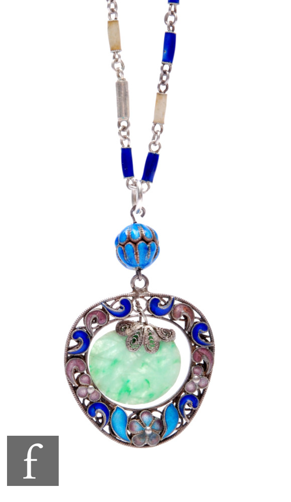 An early 20th Century low grade silver and floral enamelled decorated pendant with central carved