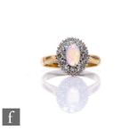 An 18ct opal and diamond cluster ring, central oval opal, length 6mm, within a border of twelve