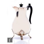 A hallmarked silver baluster coffee pot raised on four stepped feet and terminating in ebonised