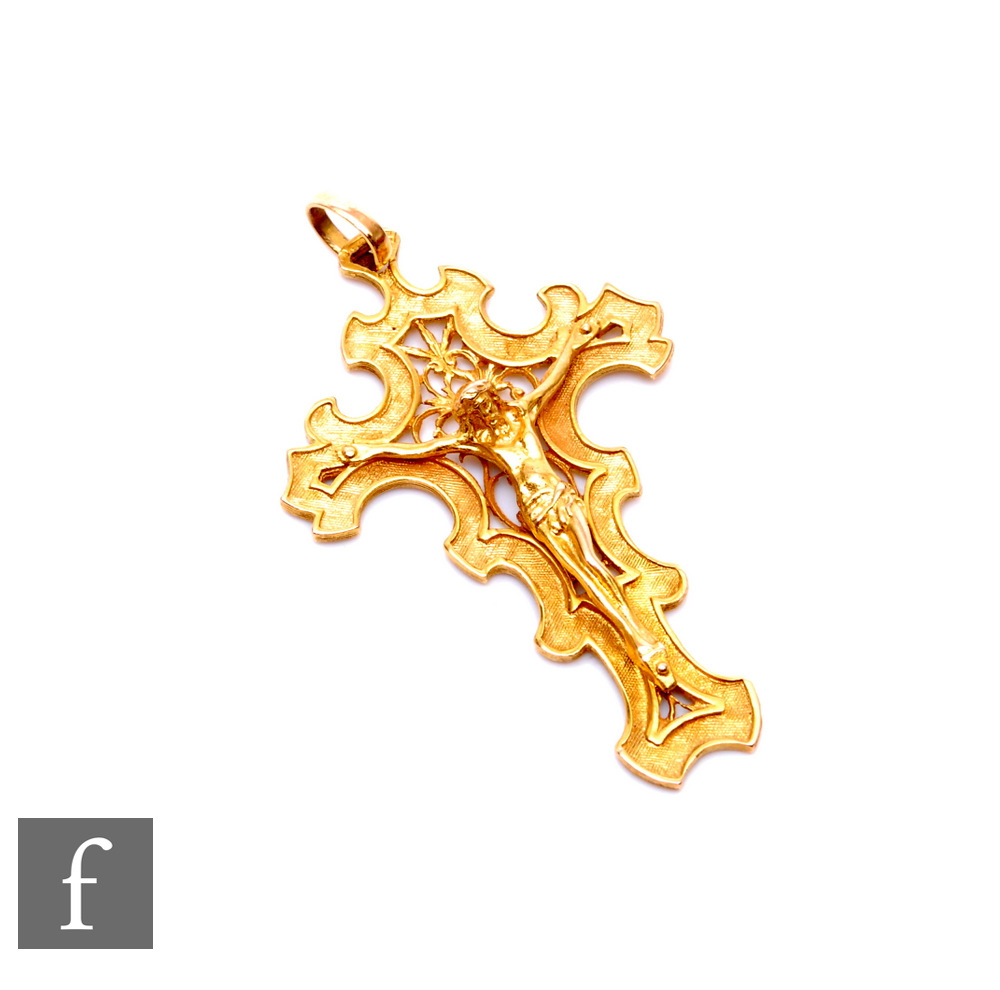 An 18ct crucifix with shaped borders, weight 8.5g, length 5.5cm, terminating in pendant loop.