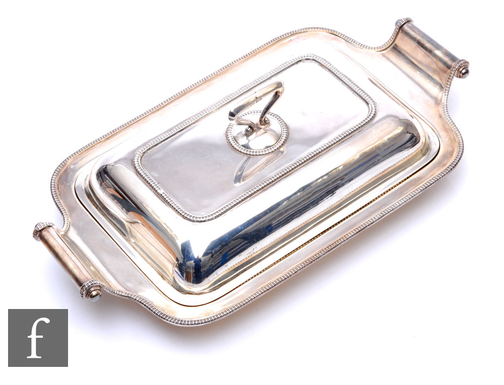 A hallmarked silver rectangular entrée dish and cover of plain form with integral side scroll