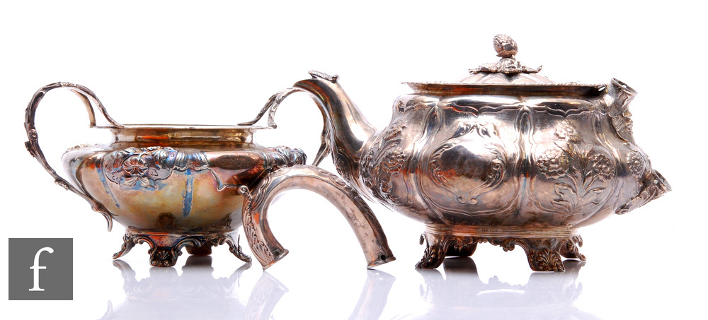 A hallmarked silver melon shaped teapot with part embossed foliate decoration raised on four