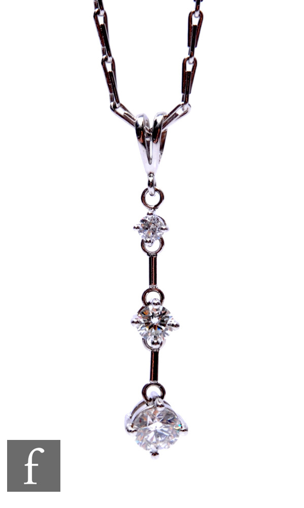 An 18ct white gold diamond pendant comprising three graduating brilliant cut, claw set stones weight