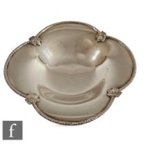A hallmarked silver shallow quatrefoil shaped bowl raised off a collet foot, with fruiting vine