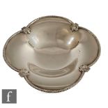 A hallmarked silver shallow quatrefoil shaped bowl raised off a collet foot, with fruiting vine