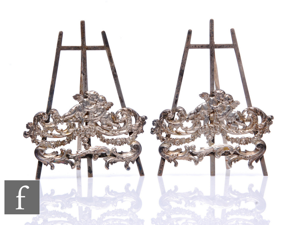 A pair of hallmarked silver menu holders modelled as easels with cherub and foliate scroll