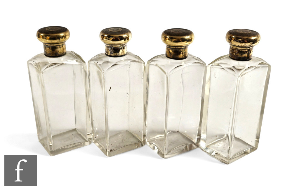 A set of four cologne bottles, plain rectangular cut shouldered bottles each terminating in a silver