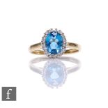 A 9ct hallmarked topaz and diamond cluster ring, central blue topaz within a diamond set border,