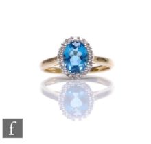 A 9ct hallmarked topaz and diamond cluster ring, central blue topaz within a diamond set border,