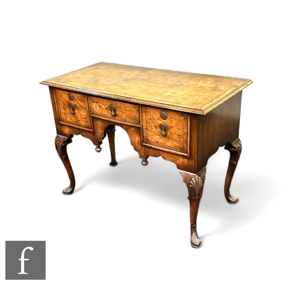 A George I style walnut lowboy, the quartered and crossbanded top over three drawers and an arch,