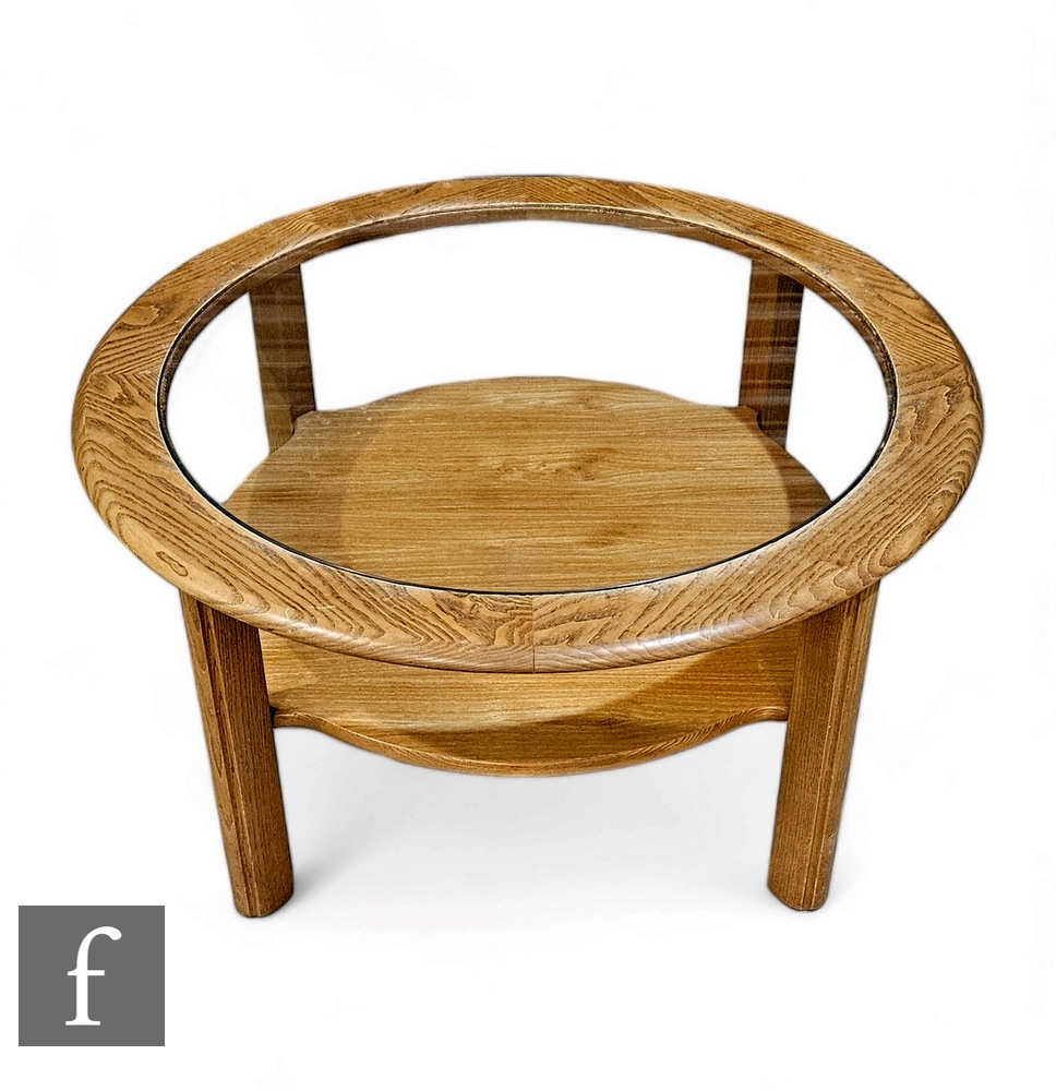 A G-Plan ash coffee table of circular from, raised on four block supports, the glass inset top above