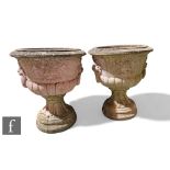A large pair of reconstituted garden urns, each of pedestal campana form with lion mask ring