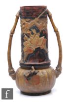 A large Bretby 'Japanese' vase, flanked by bamboo handles, relief moulded with depictions of