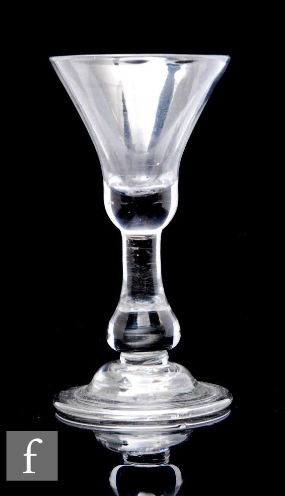 An 18th Century drinking glass circa 1720, the bell form bowl with solid base above a true