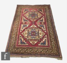 A Turkish Kars Kazak rug, red, ochre and green geometric borders, 208cm x 145cm.