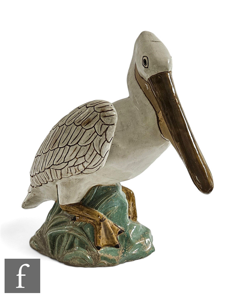 A decorative terracotta figure of a pelican, the white glazed bird, perched on a rocky outcrop,