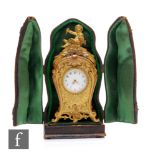 A late 19th Century French miniature travelling gilt metal mantel clock, the scrolling feet rising