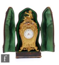 A late 19th Century French miniature travelling gilt metal mantel clock, the scrolling feet rising