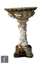 A reconstituted stone garden bird bath of pedestal form, decorated with vines and grapes, on a