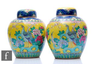 A pair of 20th Century yellow ground Chinese famille rose jars and covers, of rounded ovoid form