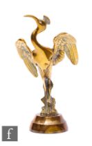 A brass model of a flamingo stretching its wings, on a circular base, possibly a car mascot,
