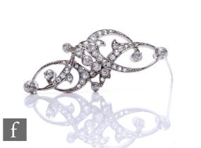 A white metal and diamond openwork brooch, stylised foliate design with a series of diamond set