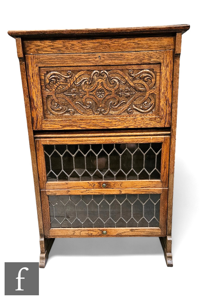 A 1920s carved oak combination bookcase, the interior enclosed by a carved panel over two