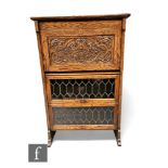 A 1920s carved oak combination bookcase, the interior enclosed by a carved panel over two