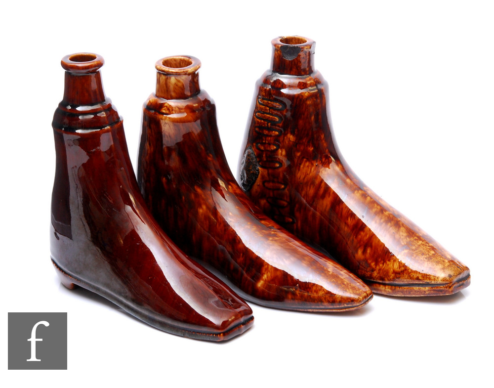 A collection of three 19th Century novelty drinking flasks modelled as boots, with all over