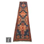 An Iranian knotted wool runner, the blue and red ground rug with a series of panels and floral