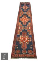 An Iranian knotted wool runner, the blue and red ground rug with a series of panels and floral