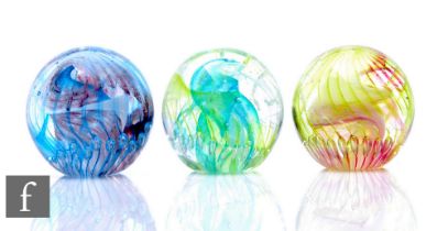 Three contemporary Isle of Wight studio glass paperweights of domed form, all internally decorated