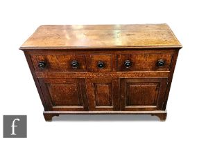 A George III oak dresser fitted with three drawers above a cupboard base, turned ebonised handles