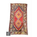 A Turkish Ortakoy woven wool rug, circa 1960, the red ground rug with central diamond lozenge,