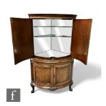 A Queen Anne style walnut floorstanding cocktail cabinet, the mirrored interior enclosed by shaped