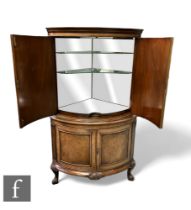 A Queen Anne style walnut floorstanding cocktail cabinet, the mirrored interior enclosed by shaped