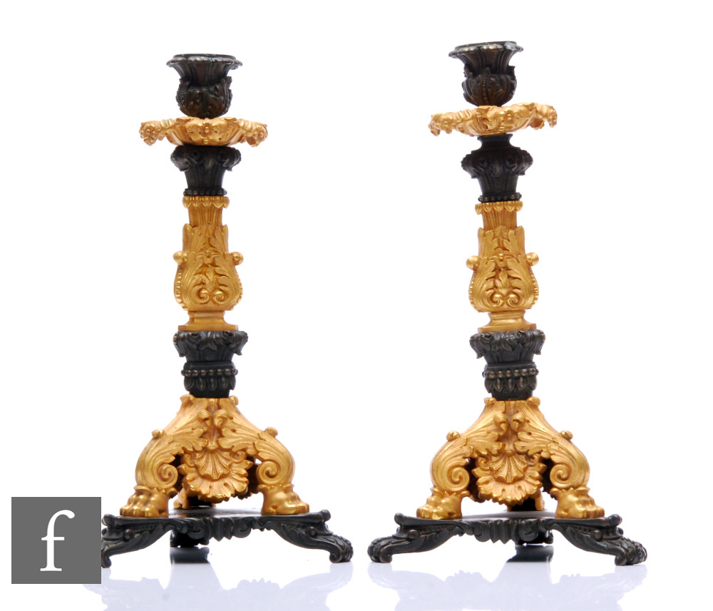 A pair of French Empire style bronze and ormolu cast bronze candlesticks, scroll feet and tricorn