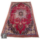 A Persian Tabriz carpet, the red ground rug with central arabesque deigns, within geometric designs,