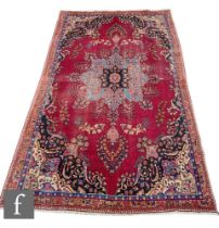 A Persian Tabriz carpet, the red ground rug with central arabesque deigns, within geometric designs,