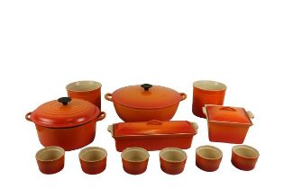 A large circular two handled orange decorated Le Creuset Pot and Cover, a smaller ditto with