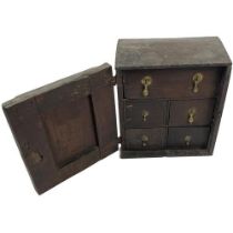 An early 18th Century English oak Spice Cabinet, the panelled door with brass drop handle opening to