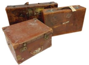 Two similar antique leather Suitcases, (labels of travel locations and hotels) together with a